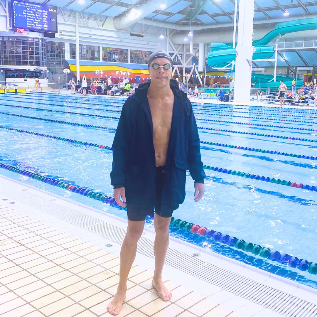 Male swimmer wears a navy blue swim parka to keep his muscles warm before a race