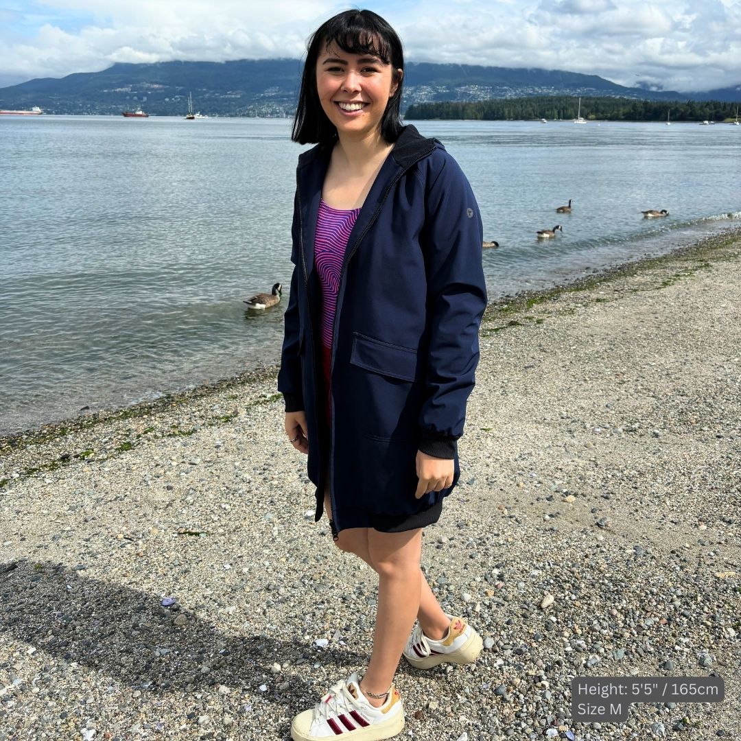 female swimmer wears a navy blue swim parka over her purple swim suit at the beach