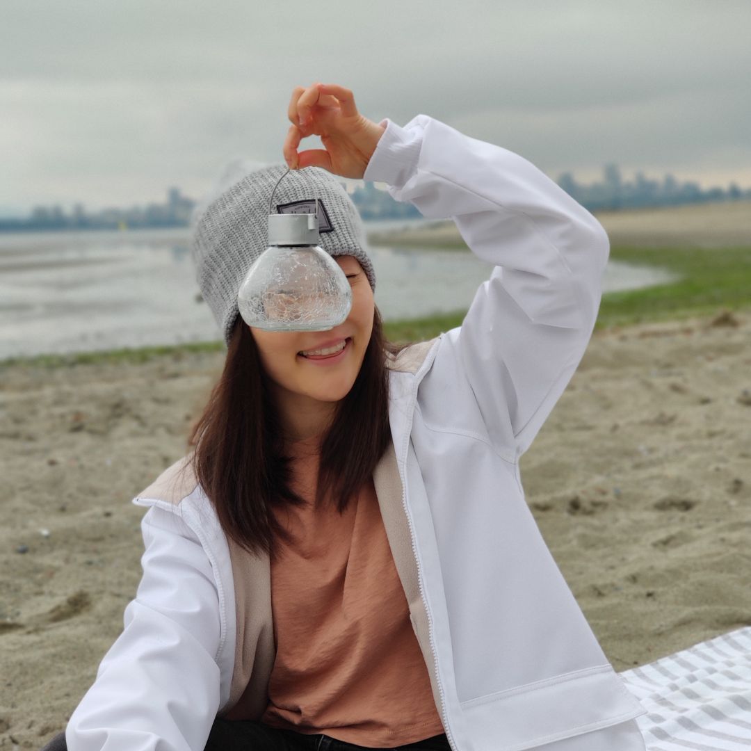 Katie Lee holding a small lamp on Jericho Beach