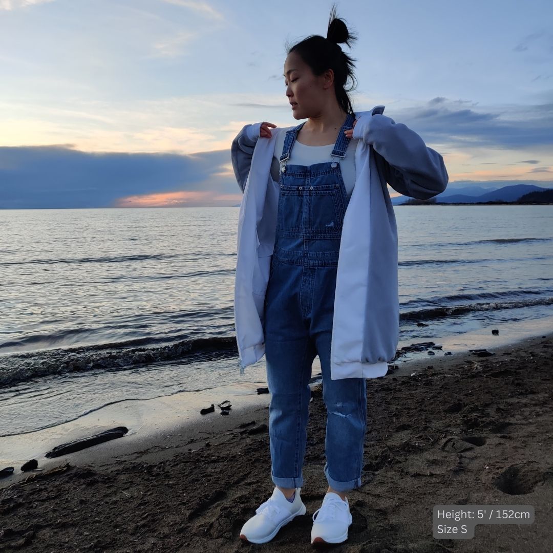 Female model wears white swim parka with denim overalls