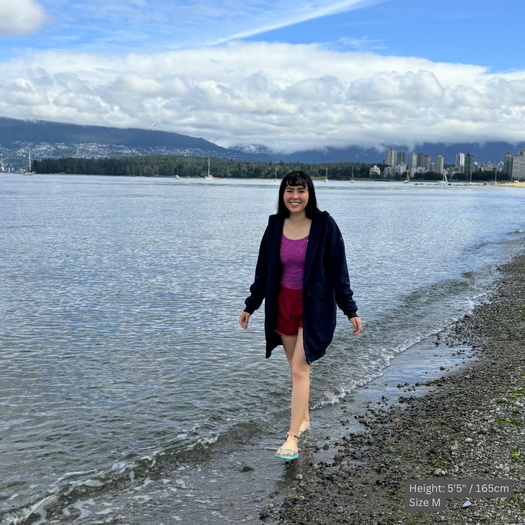 Female swimmer wears a navy blue swim parka over her swim suit to stay warm at the beach