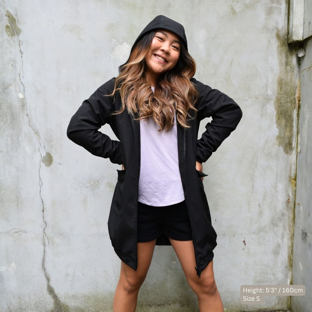 Female athlete wears a black swim parka over lilac t-shirt and black running shorts