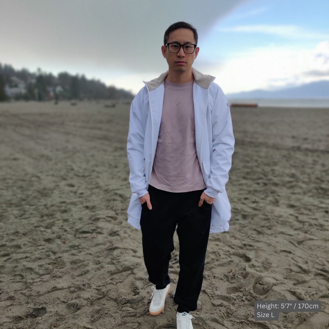 male model wears a white swim parka at the beach